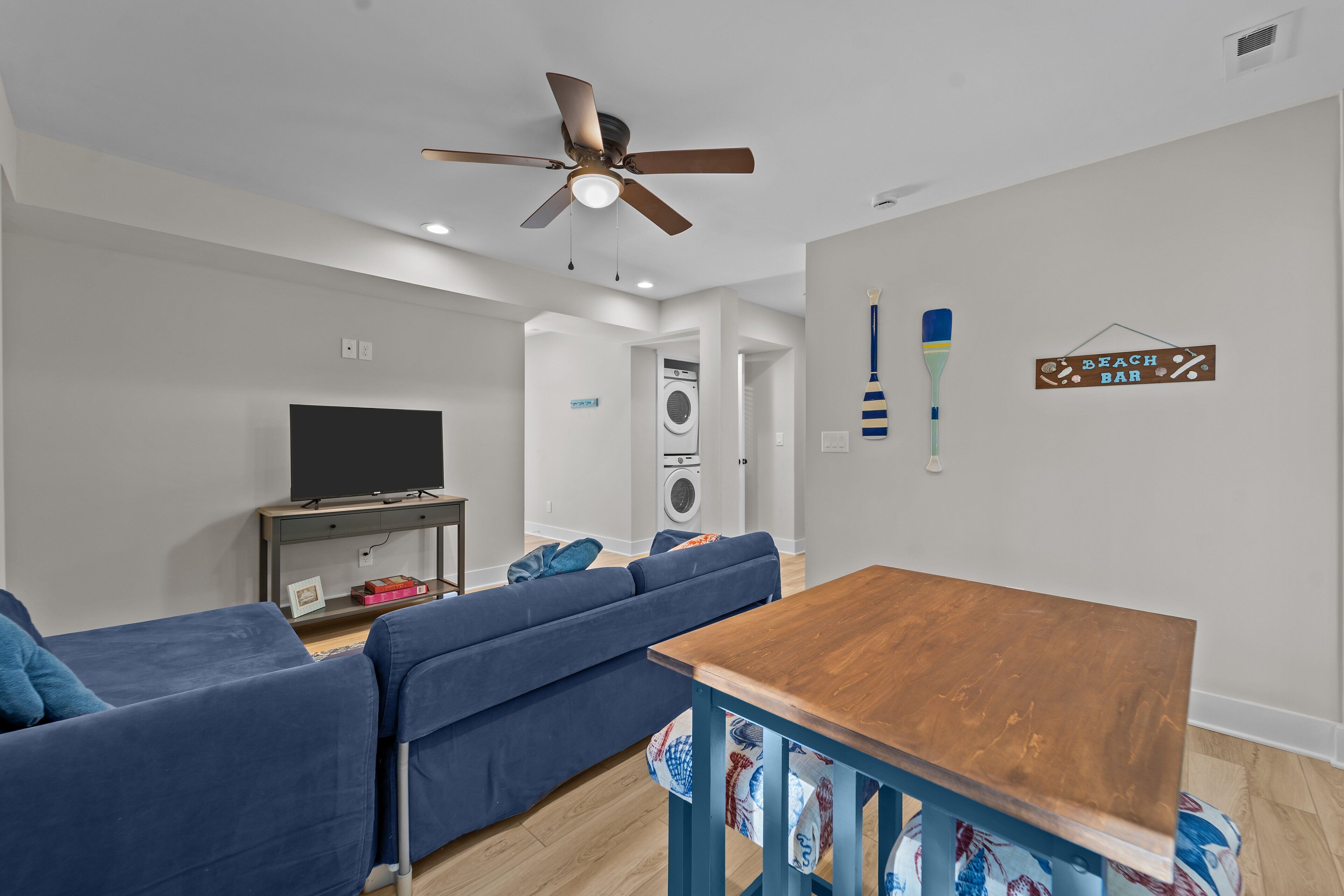 A modern living room with a sofa, a wooden table, a ceiling fan, and a television.