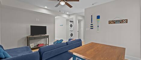 A modern living room with a sofa, a wooden table, a ceiling fan, and a television.