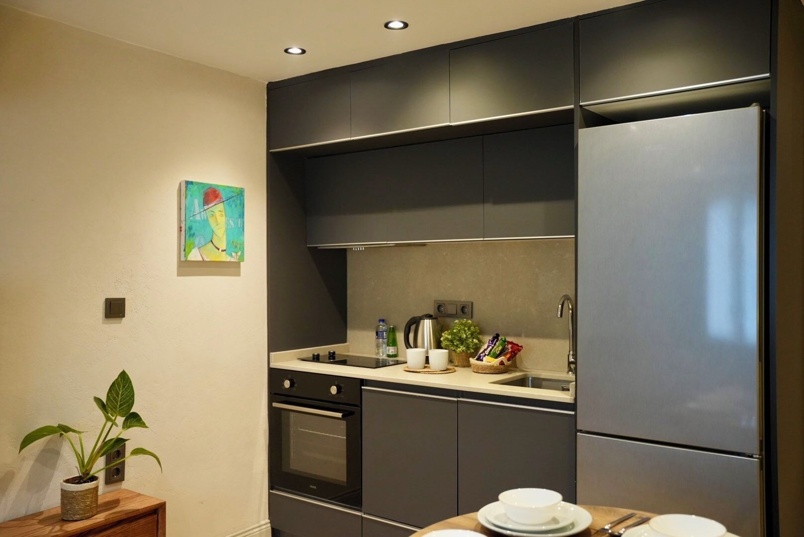 Eine moderne Küche mit dunklen Schränken, einem eingebauten Backofen und einem Edelstahl-Kühlschrank.