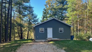 Une petite cabane à un seul étage, avec une allée en gravier menant à une porte en bois.