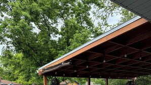Un patio techado con una parrilla, asientos exteriores y ventiladores colgantes.