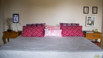 A bed with patterned pillows, a bedside table with a lamp, and a framed picture on the wall.