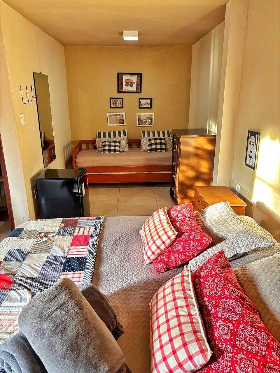 Ein Zimmer mit zwei Betten, einem Schreibtisch und einem Stuhl. An der Wand befinden sich Bilder in Rahmen.