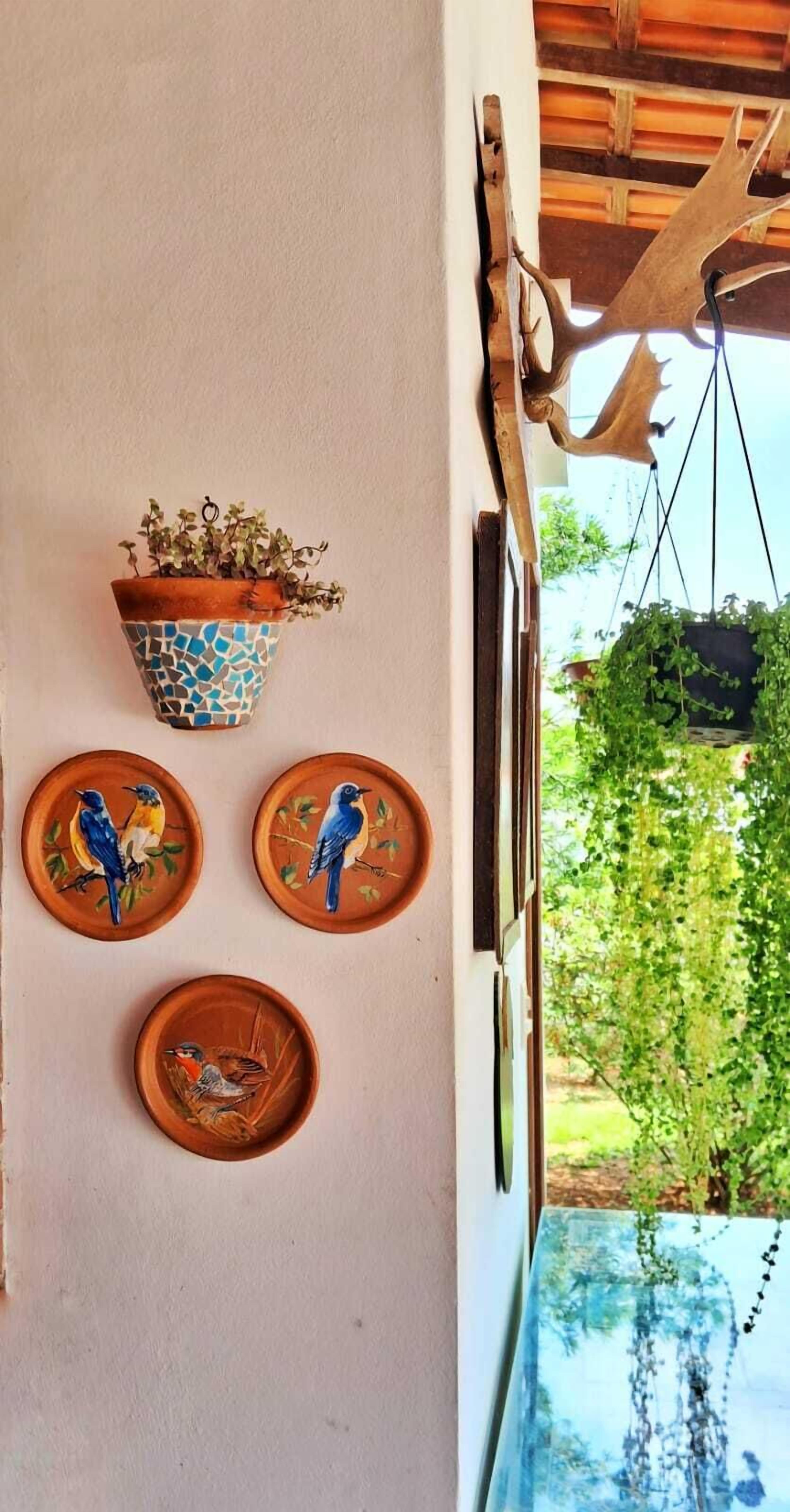 Paret amb test mosaic, tres plats amb motius de pássars i un penjoll de corçó de cérvol.
