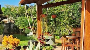 Un jardín con plantas en macetas, una pérgola de madera y mobiliario exterior.