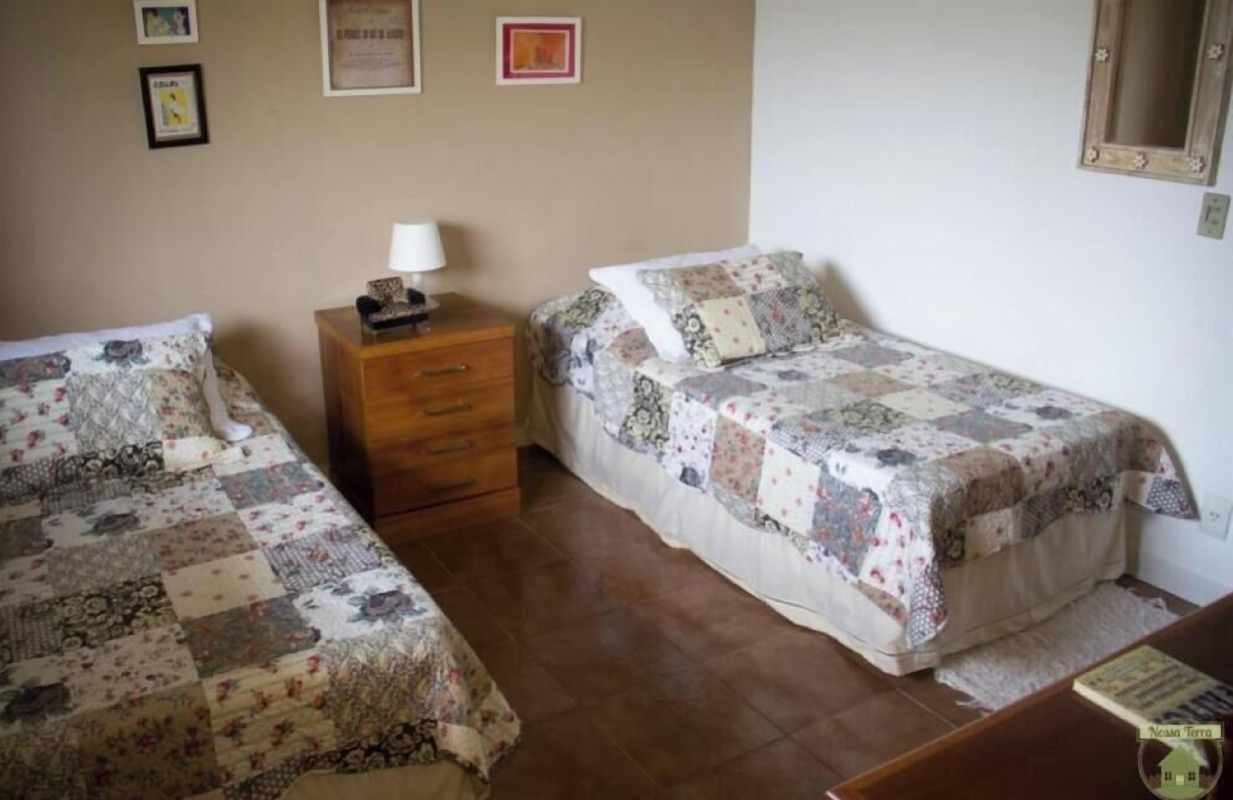 Un dormitorio con dos camas, una mesita de noche y una pequeña mesa con lámpara.