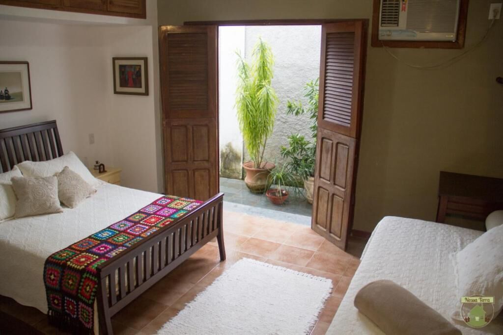 Een slaapkamer met een bed, een bankje, een bloempot en uitzicht op het omliggende landschap.