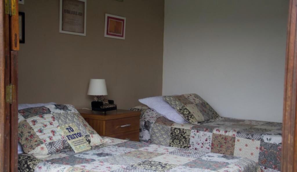 A bedroom with two beds, a nightstand, a lamp, and a framed certificate on the wall.