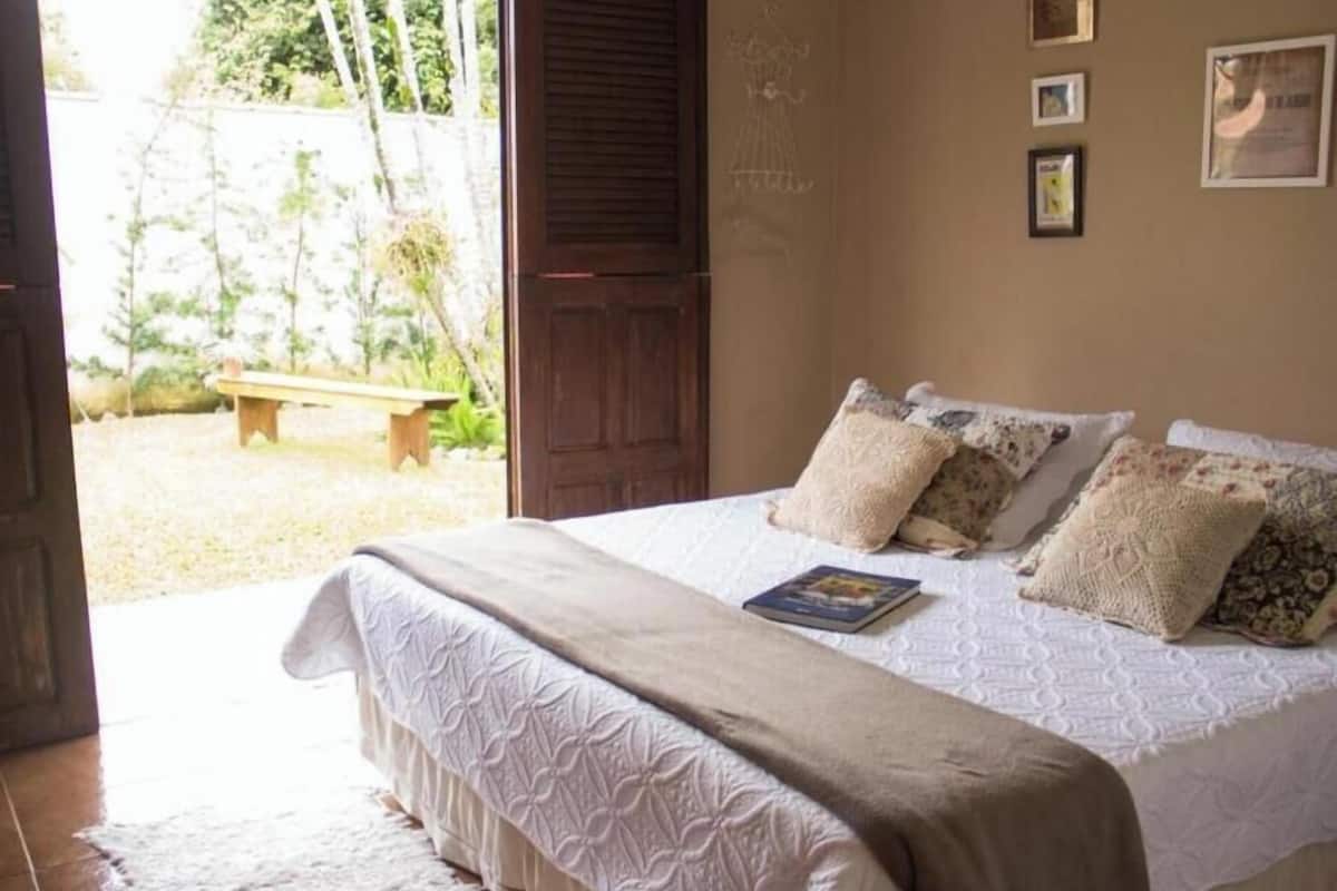 Un dormitorio con cama, almohadas, una manta y un libro.