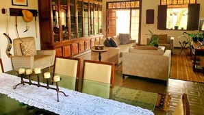 Una sala de estar con una mesa de centro de vidrio, dos sofás, un mueble con puertas de cristal y un ventilador de techo.