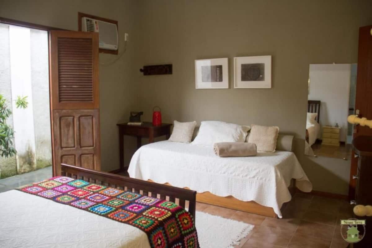Un dormitorio con cama, mesita de noche, espejo y puerta.