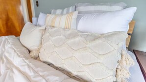 Ein Bett mit weißer Bettwäsche und einer gewebten Decke.
