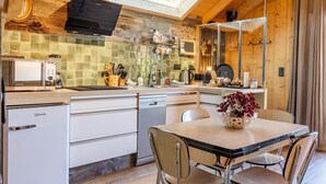 Una cocina moderna con microondas, tostadora y cafetera. Hay una mesa de comedor con sillas y un jarrón de flores.
