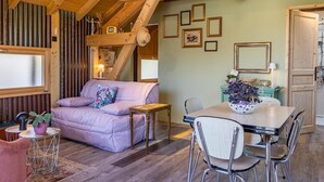 Una habitación acogedora con techo de madera, un sofá, una mesa de comedor con sillas y una ventana.