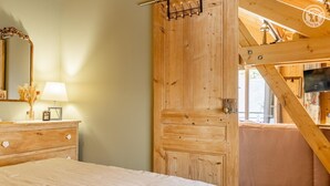 Un dormitorio de madera con cama, cómoda y una amplia puerta de madera.