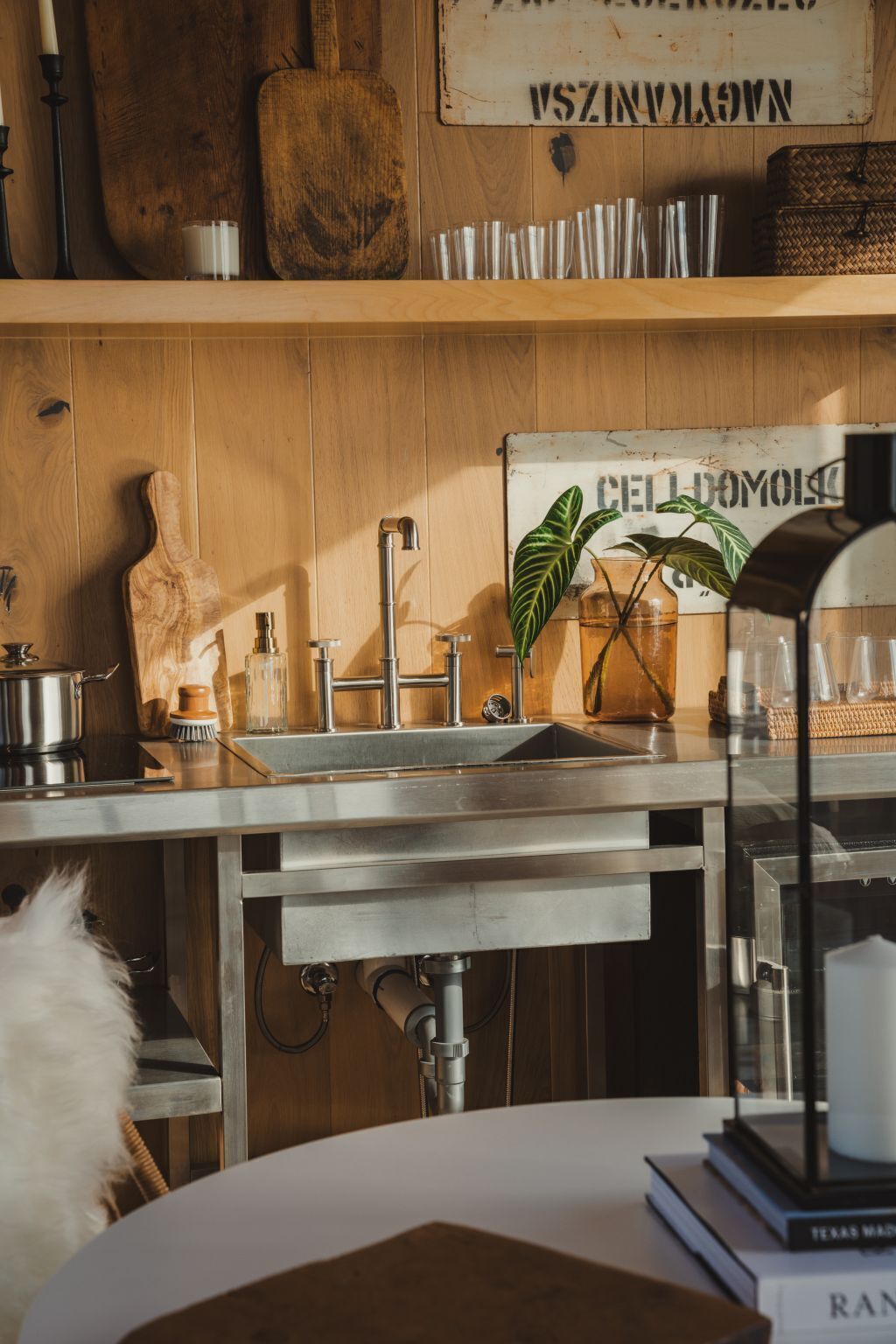 Une cuisine dotée d’un évier en acier inoxydable, de meubles en bois et d’un mur en bois au style rustique.