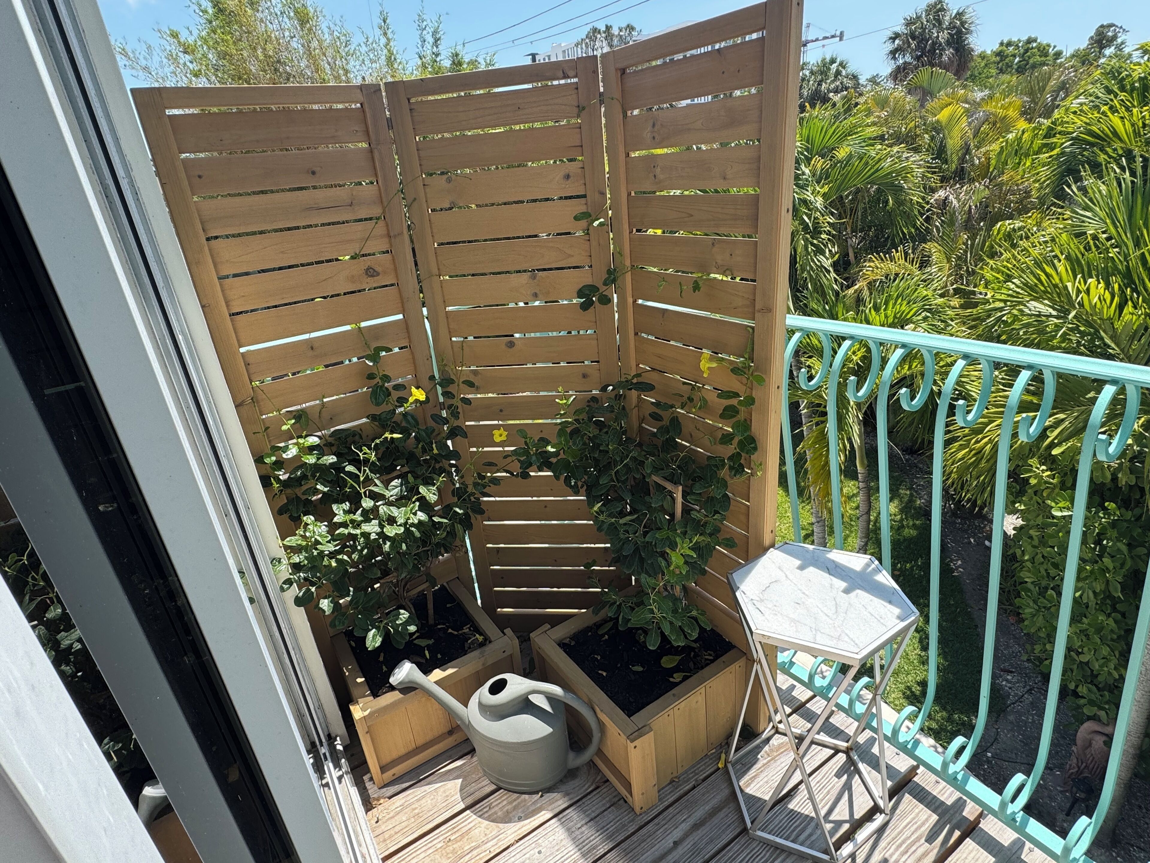 A wooden deck with raised garden beds, a small table, and a metal railing.