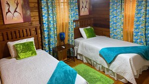 Quarto com duas camas, paredes de madeira e cortinas estampadas.