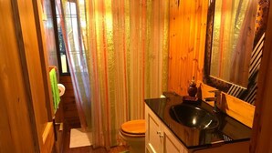 Um banheiro compacto com toucador de madeira, pia e vaso sanitário.