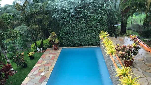 Uma piscina retangular com borda de pedra e um caminho de pedra que a leva até ela.