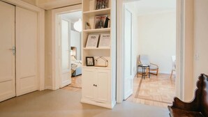 A spacious hallway with a white cabinet, a wooden bench, and a chair.