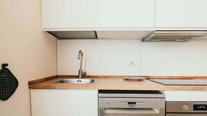 A kitchen with white cabinets, a stainless steel sink, a dishwasher, and a wooden countertop.
