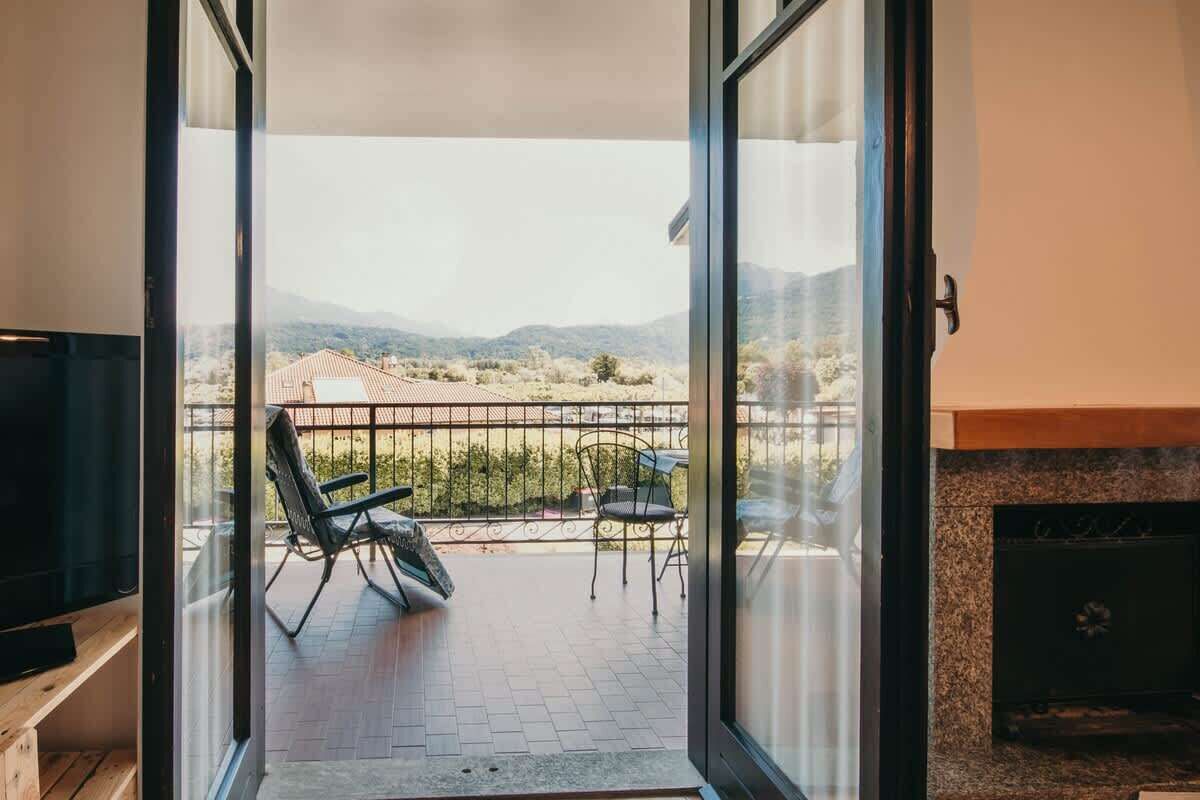 Un balcone con vista su un paesaggio montuoso, un camino e posti a sedere all'aperto.
