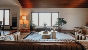 A living room with a wooden ceiling, a sofa, a coffee table, a lamp, and several potted plants. - LAKESIDE CITY GETAWAY (Roseville)