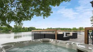 A hot tub on a wooden deck with a view of a lake and a gazebo with seating. - LAKESIDE CITY GETAWAY (Roseville)