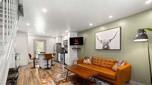 A modern living room with a sofa, coffee table, and a TV mounted on the wall.