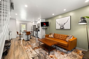 Un salon moderne avec un canapé, une table basse et un téléviseur fixé au mur.