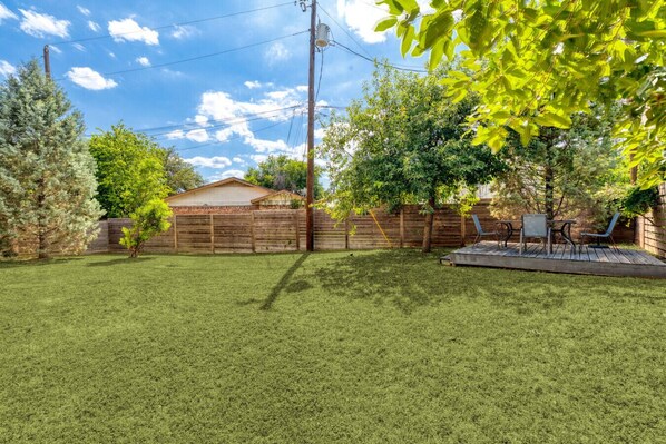 A backyard with a wooden fence, a patio with outdoor furniture, and a house in the background. - Retro SoCo GetawayTownhome! (Austin)