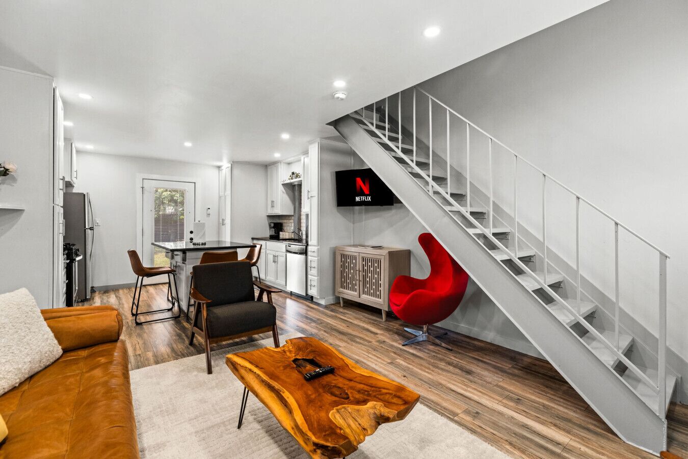 Un salon moderne avec un escalier, un coin repas et une cuisine.
