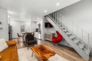 A modern living room with a staircase, a dining area, and a kitchen. - Retro SoCo GetawayTownhome! (Austin)