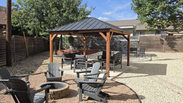 An outdoor patio with a wooden pergola, seating area, and a fire pit. - Retro SoCo GetawayTownhome! (Austin)