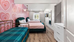 A room with two beds, a large window, a wardrobe, and a pink heart-patterned wall. - Pink Palace SoCo Dream Townhome! (Austin)
