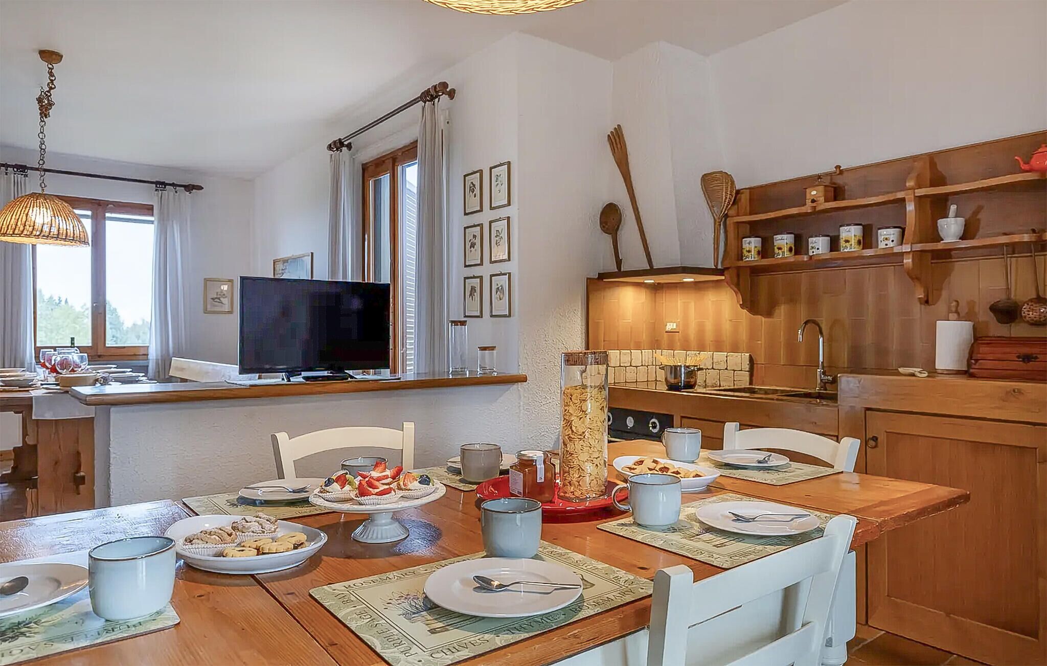 A cozy kitchen with wooden cabinets, a dining table set for four, and a television on a stand.