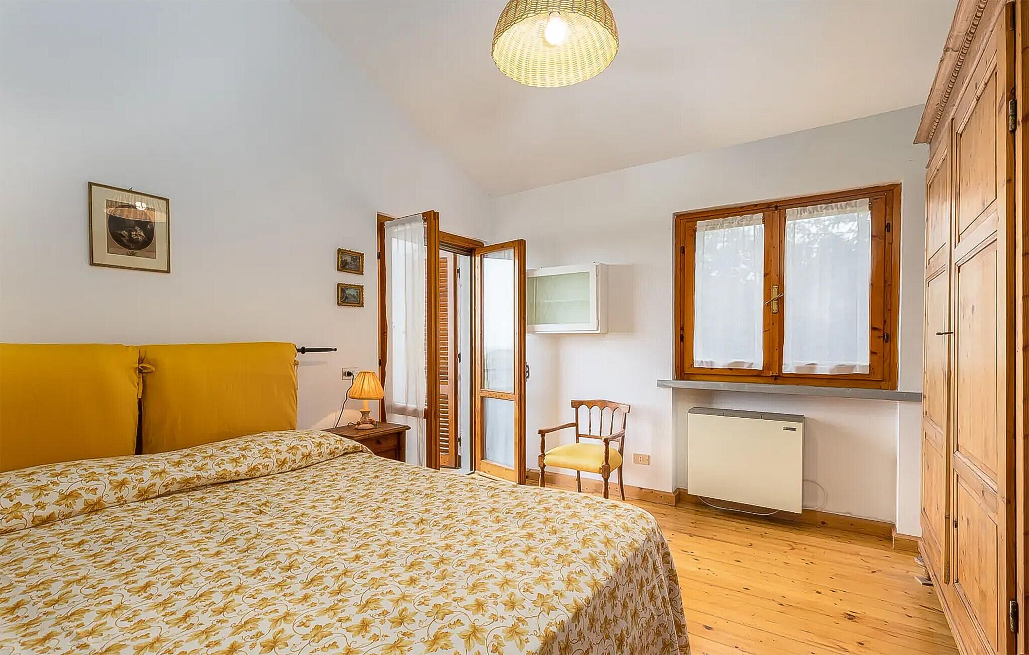 A bedroom with a bed, a chair, a radiator, and wooden cabinets.