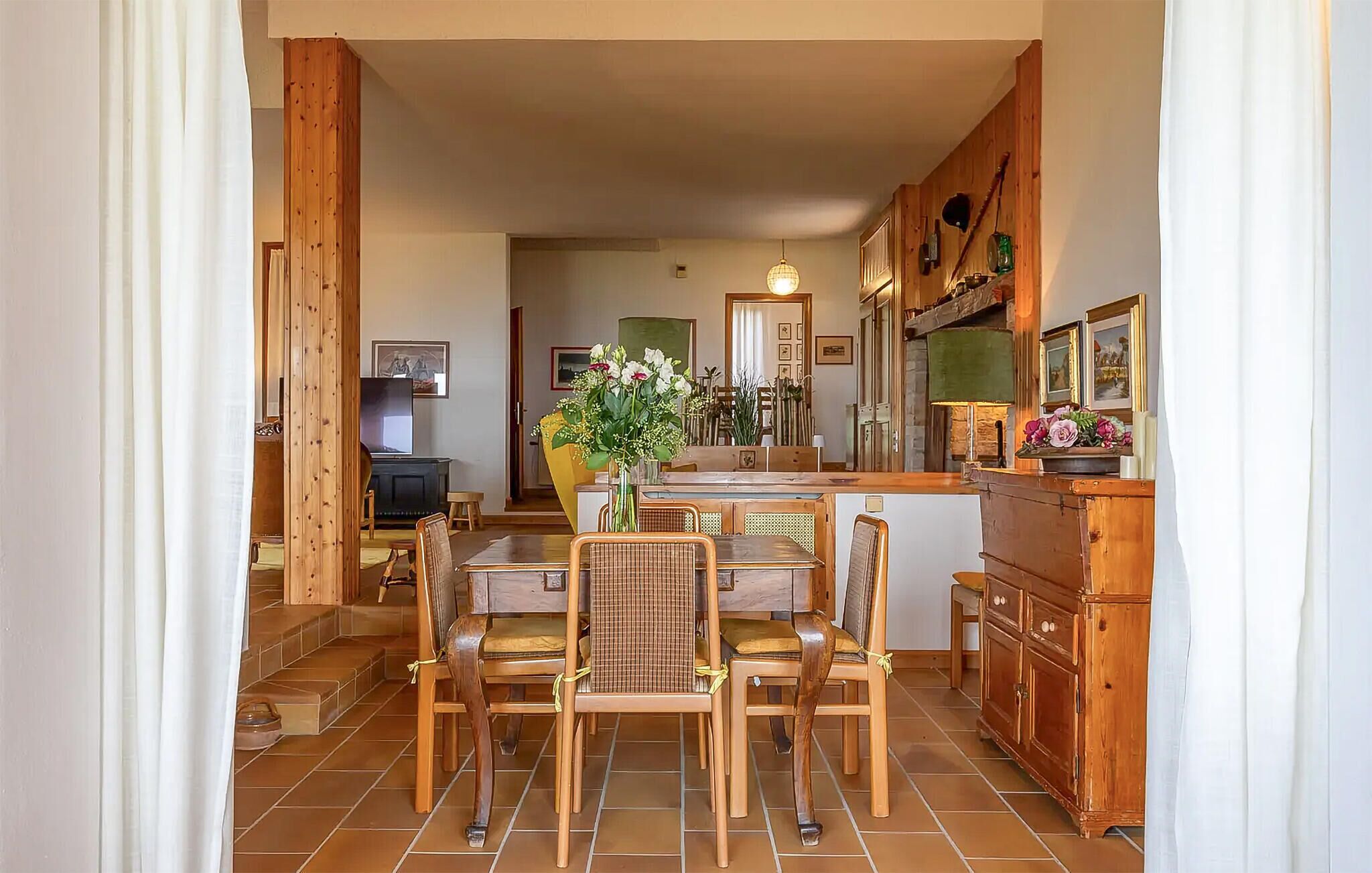 Un espace de restauration accueillant et bien éclairé, avec des meubles en bois et une table centrale, entourée de chaises.