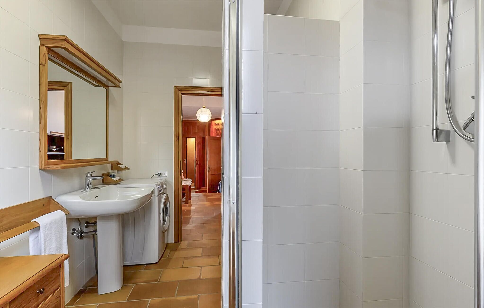 Une salle de bain avec deux lavabos, un miroir, une douche et un sol carrelé.