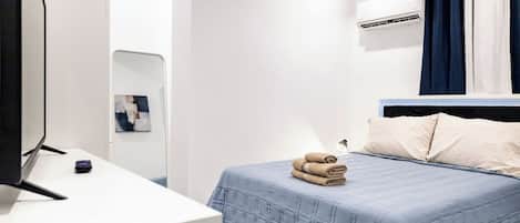 Un dormitorio con una cama, una mesita de noche, un espejo y un aire acondicionado instalado en la pared.