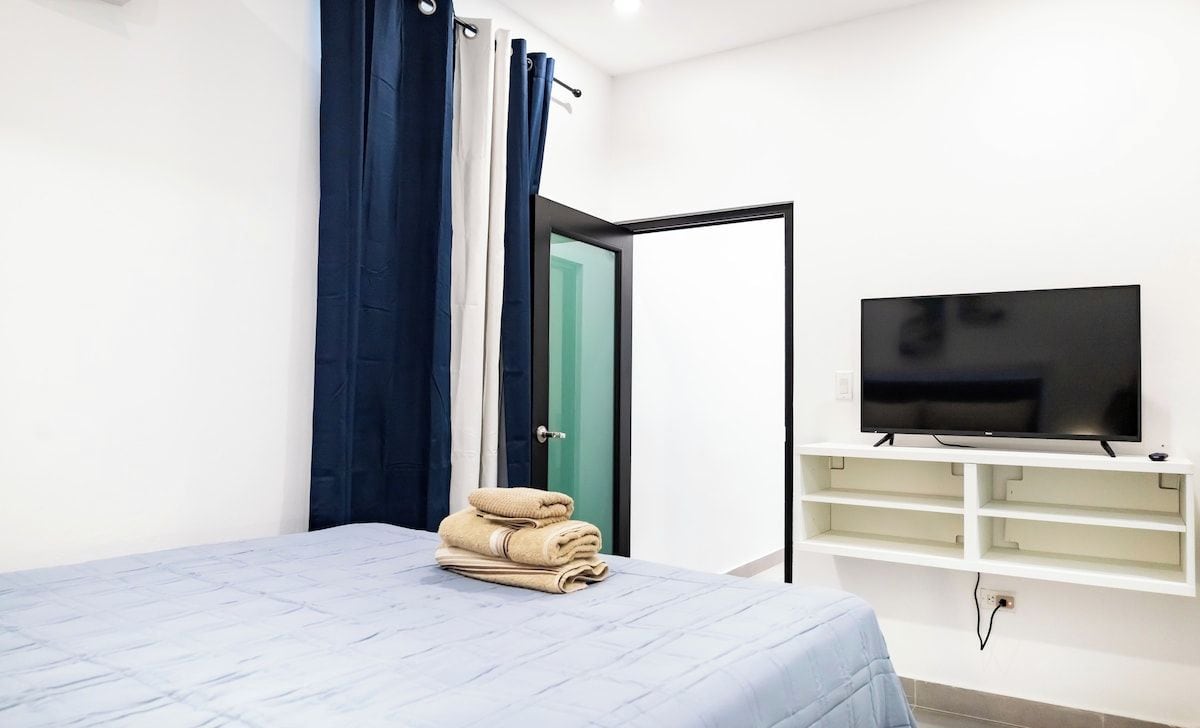 Ein Hotelzimmer mit einem Bett, einem Fernseher auf einem Schrank und einer Tür zu einem anderen Raum.