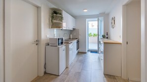 En smal hall leder in till ett kök med vita köksskåp, en mikrovågsugn och ett litet kylskåp.