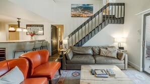 Una sala de estar moderna con una escalera, un sofá, una mesa de centro y un comedor.