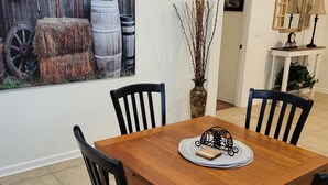 A dining area with a wooden table and four chairs, a vase with branches, and a rustic wall art piece. - Charming 2BD / 1 BA farmhouse on 2.5 acres w/mountain views in fabulous Glendale (Glendale)