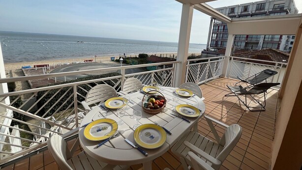 A balcony with a table set for four, overlooking a beach and the sea. - Seafront T3 Apartment in Arcachon with Secure Parking (Arcachon)
