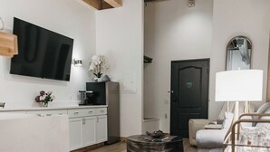 Una cocina moderna con televisión de pantalla plana, vigas de madera y un comedor con mesa redonda y sillas.