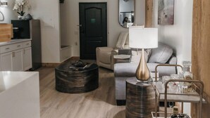 Una sala de estar moderna con techo de madera, un sofá, una mesa de centro y un comedor con un estante de metal.