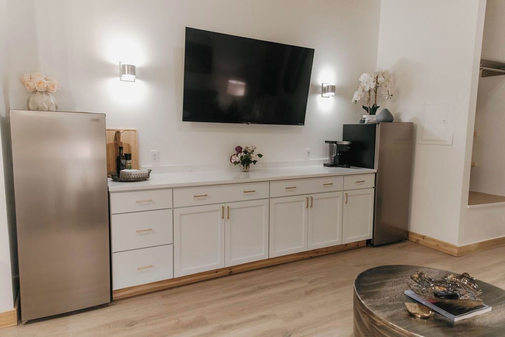 Una cocina moderna con una televisión de pantalla plana sobre la encimera, electrodomésticos de acero inoxidable y suelo de madera.