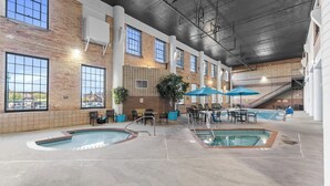 Un área de piscina interior con varias piscinas, zonas de estar y una escalera.